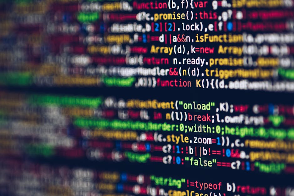 Close-up image of a computer screen displaying lines of colorful programming code with various functions, variables, and syntax highlighted in red, green, blue, and yellow. The screen appears slightly