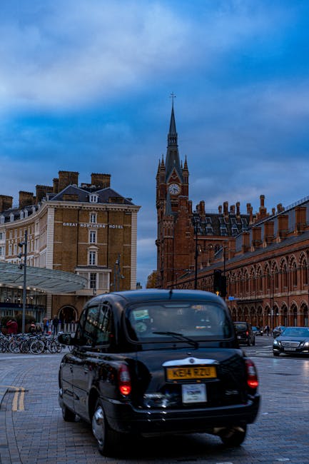 The interior architecture of St Pancras station features a large, curved metallic roof structure supported by blue-painted steel arches, with a combination of red brick walls and arched windows along 